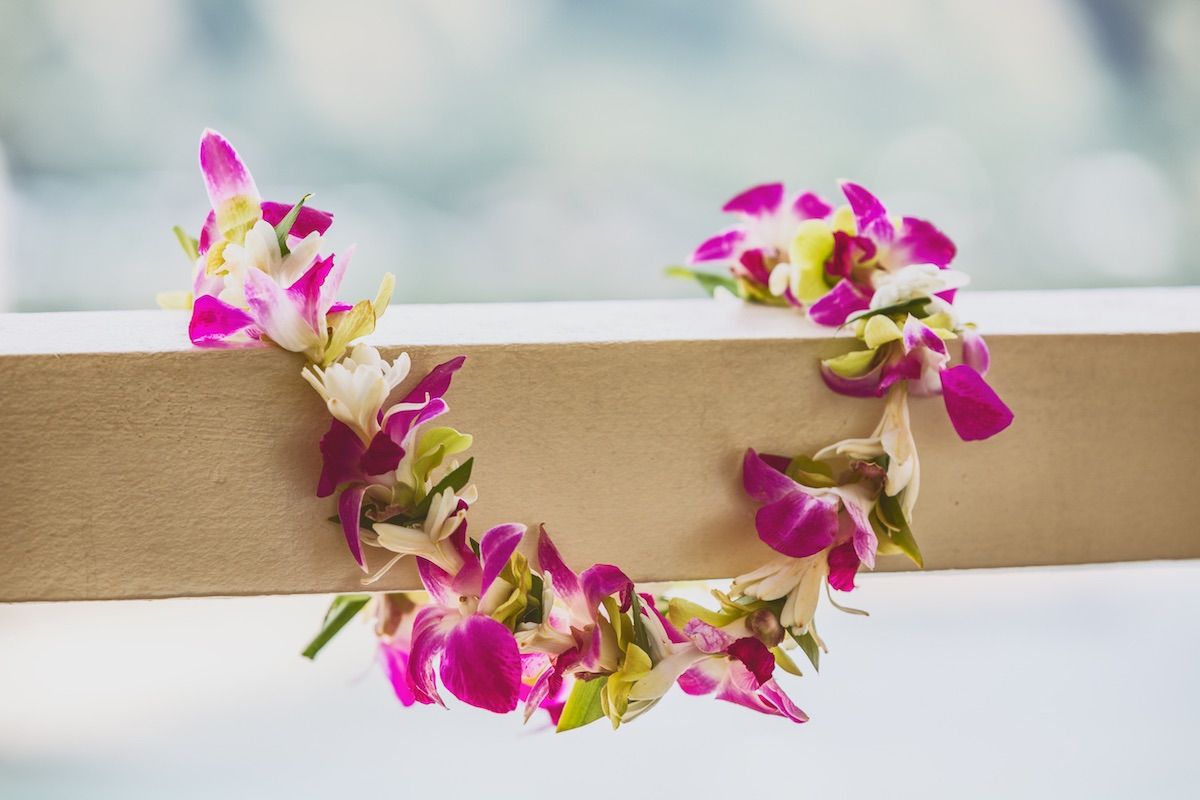 Find out how to book a lei greeting in Honolulu with tips by top Hawaii blog Hawaii Travel Spot. Image of a fresh flower lei on a railing