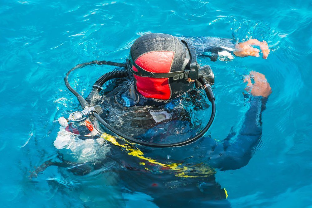 The scuba diver dives into the water, closeup view