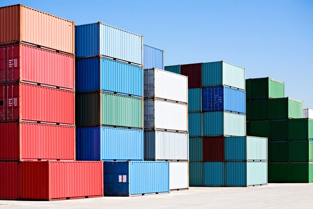 Cargo shipping containers stacked at harbor freight terminal under clear blue sky