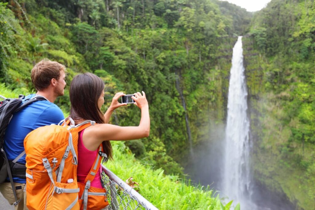 Check out this state and national parks in Hawaii list by top Hawaii blog Hawaii Travel Spot! Image of a couple taking a photo at Akaka Falls on the Big Island.
