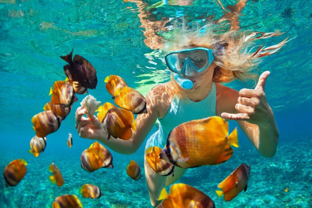 Find out which is the best Hawaiian island for snorkeling according to top Hawaii blog Hawaii Travel Spot! Image of Happy family - girl in snorkeling mask dive underwater with tropical fishes in coral reef sea pool. Travel lifestyle, water sport outdoor adventure, swimming lessons on summer beach holiday with kids