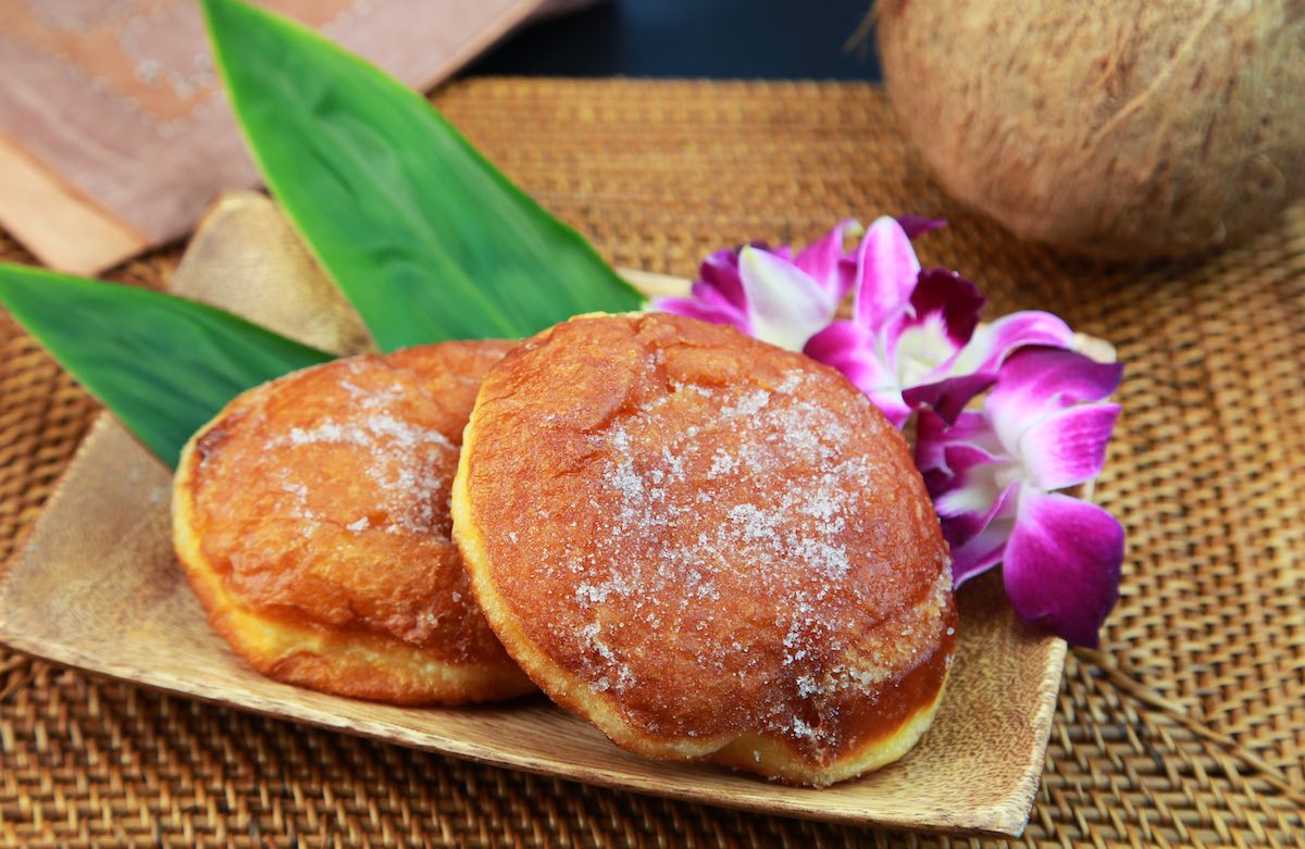 Find out where to find the best malasadas in Oahu by top Hawaii blog Hawaii Travel Spot. Image of golden brown malasadas on a plate