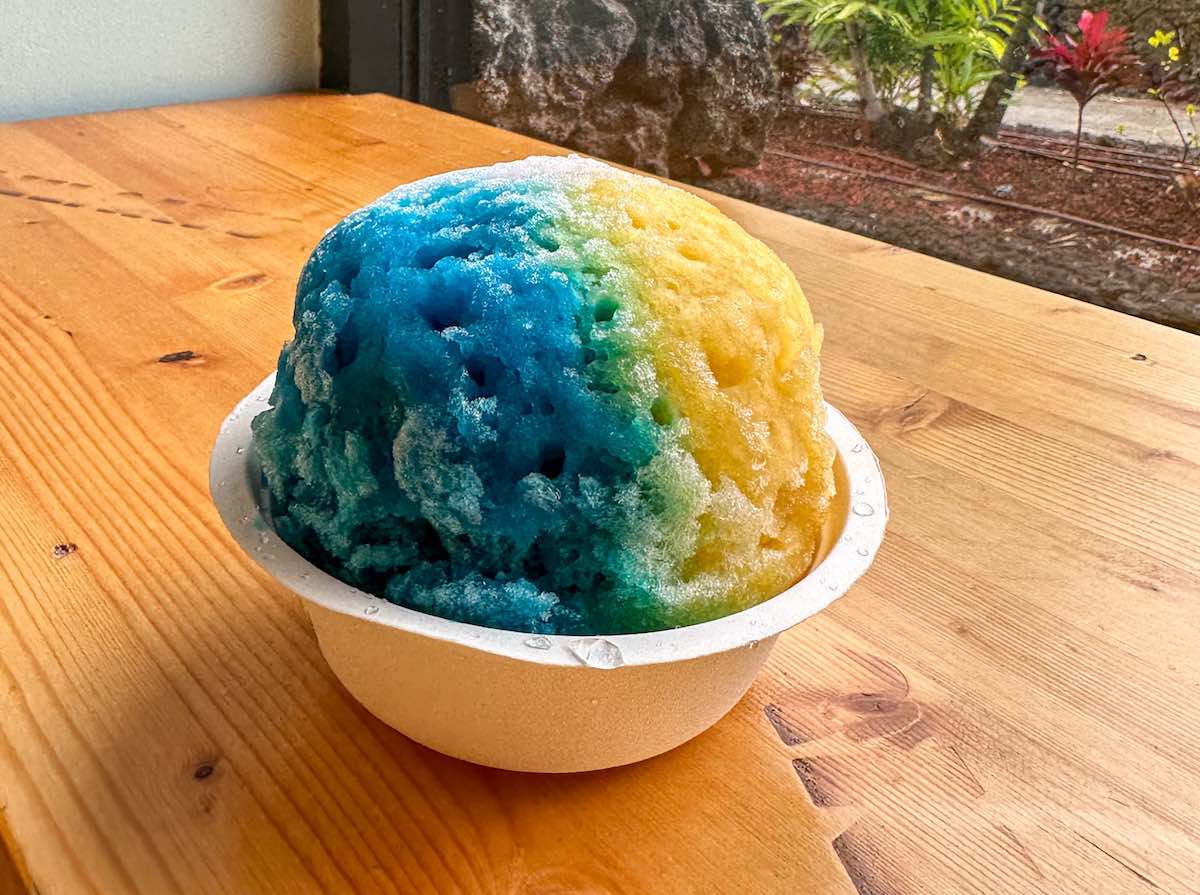 Check out this list of Big Island shave ice spots by top Hawaii blog Hawaii Travel Spot. Image of blue and yellow shave ice from Ululani Shave Ice in Kona. Photo credit: Marcie Cheung publisher of HawaiiTravelSpot.com