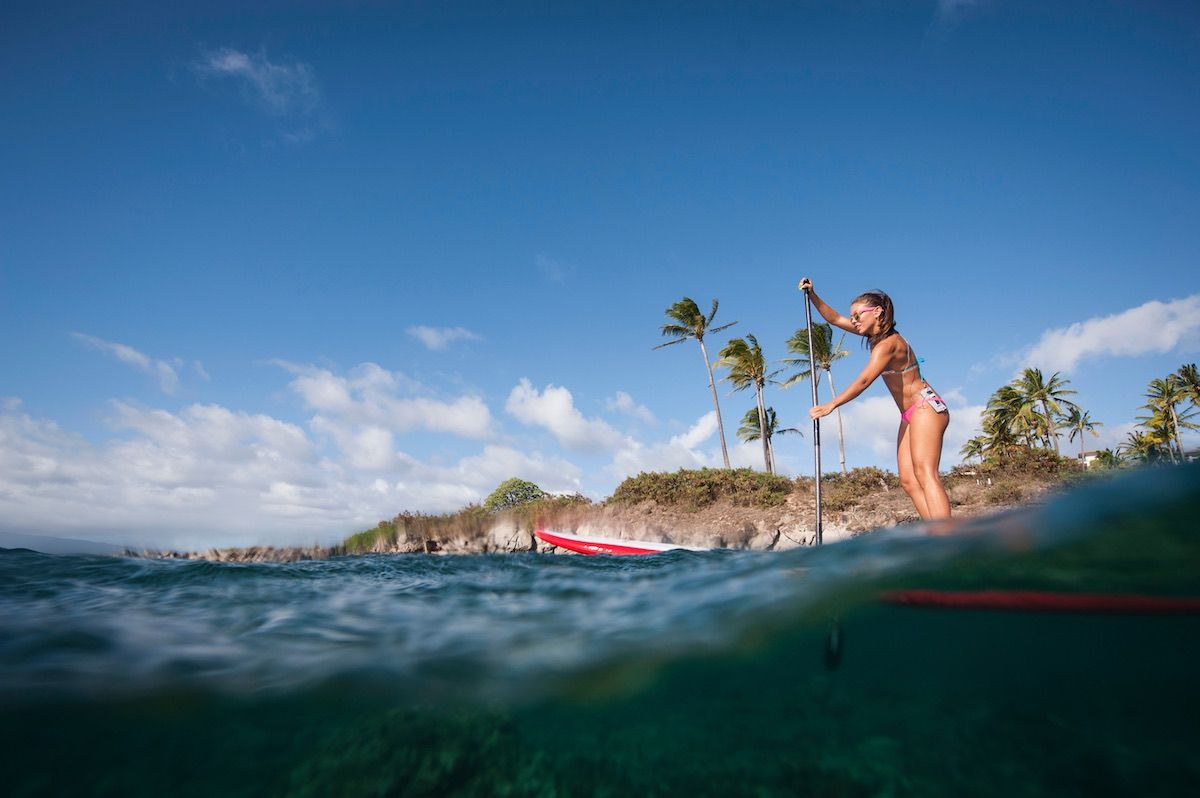 Check out the best things to do in Hawaii in April recommended by top Hawaii blog Hawaii Travel Spot! Image of a Woman paddleboarding on ocean