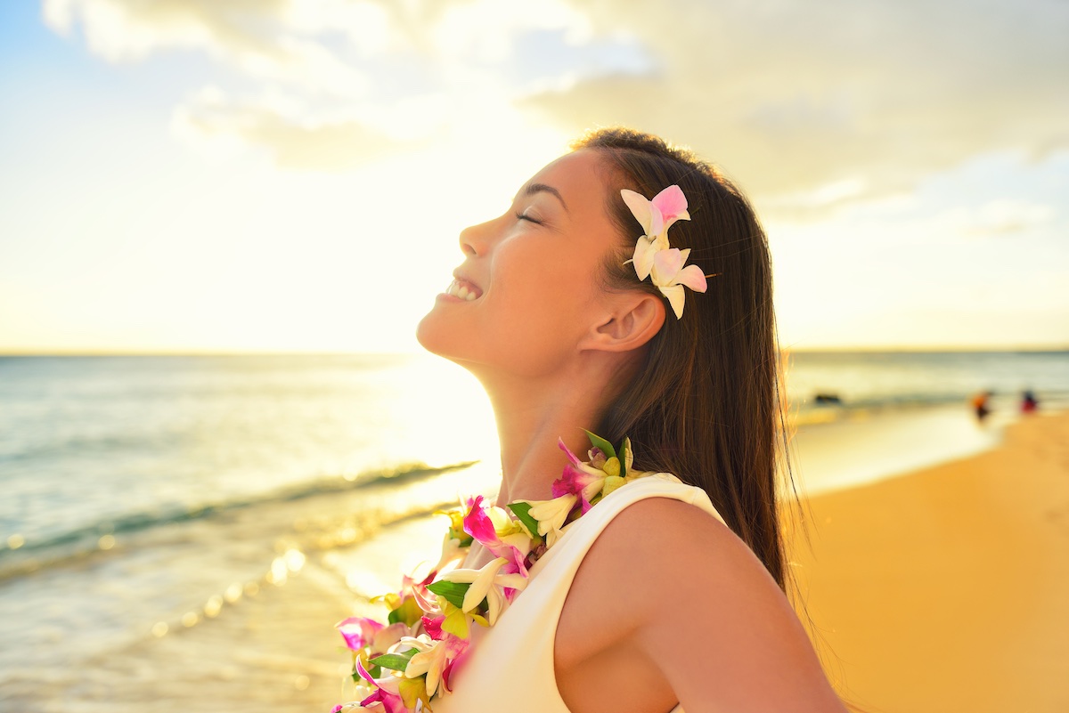 Find out the best time to visit Hawaii recommended by top Hawaii blog Hawaii Travel Spot. Image of Happy carefree woman free relaxing in Hawaii on hawaiian beach vacation. Beautiful woman in the golden sunshine glow of sunset breathing fresh air enjoying peace, serenity in nature.