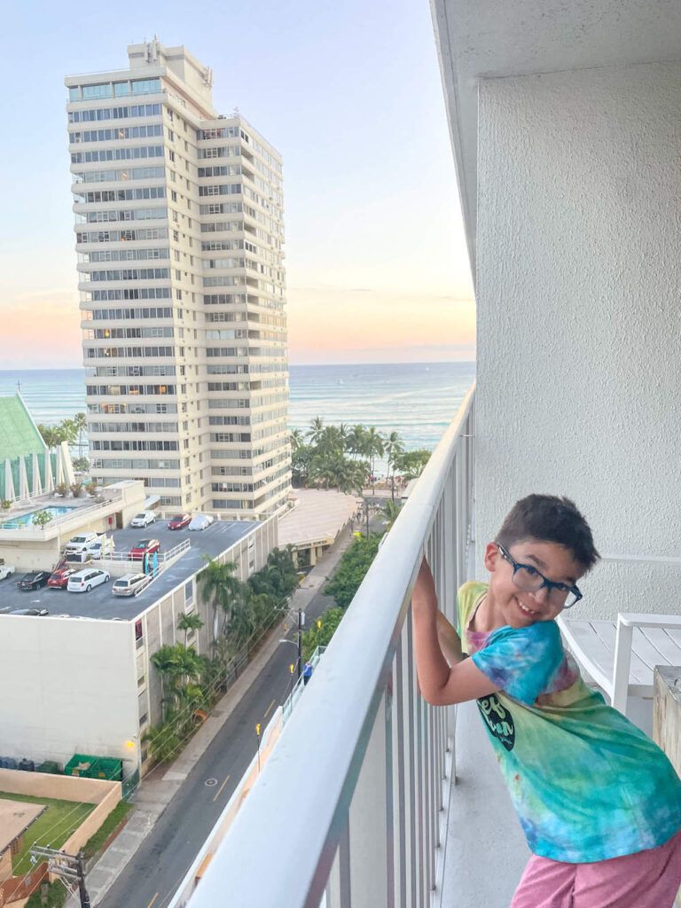 Image of a boy on a lanai in Hawaii with a view of the ocean and Waikiki