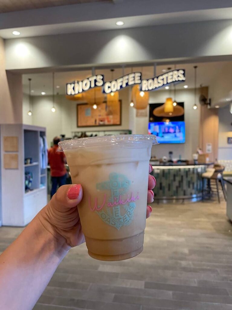 Image of an iced coffee in front of Knott's Coffee Roasters sign at the Queen Kapiolani Hotel in Waikiki
